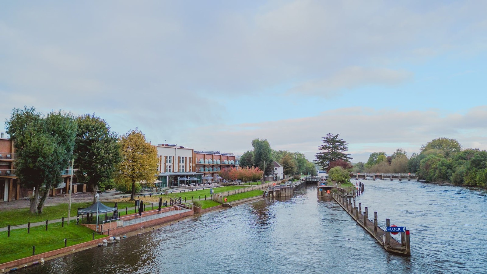 A tranquil stretch of the Thames framed by lush greenery and charming riverside architecture, capturing the serene beauty surrounding the hotel.