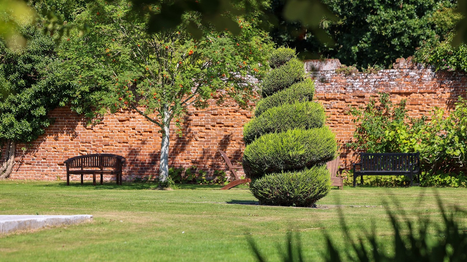 Take a seat and enjoy a moment of calm in this peaceful garden, complete with a charming topiary tree.