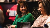 Two women at a table, smiling and enjoying each other's company during a BBC History Magazine weekend event.