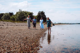A group of people walking along the sandy beach at Sinah Warren, enjoying the sunny day and ocean views.