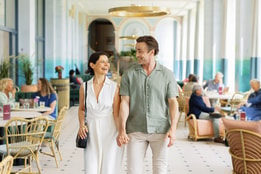 A couple strolls hand-in-hand through the elegant dining area of Heythrop Park Hotel, enjoying a romantic evening together.