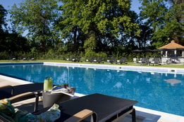The outdoor pool at The Runnymede on Thames Hotel, featuring a sun lounger and a cocktail that has been brought over from the Lounge bar
