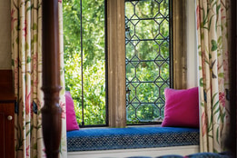 Historic hotel bedroom window seat with leaded glass windows and garden views.