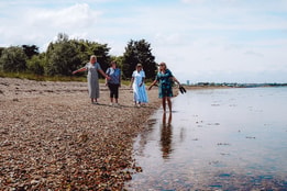 A group of people walking along the sandy beach at Sinah Warren, enjoying the sunny day and ocean views.