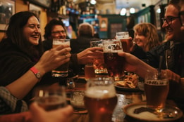 People toast with pints of beer as they smile and celebrate together
