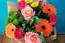 A vibrant bouquet of assorted flowers beautifully arranged in a rustic paper bag, adding charm to any setting.