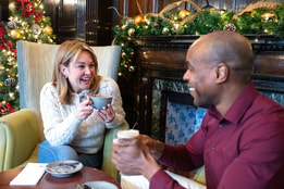 Two guests smiling at each other with hot drinks in hand