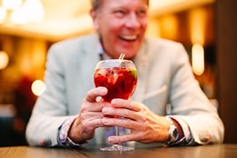A guest laughing as he holds his festive cocktail