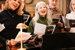 A group of guests carol singing and smiling