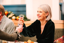 A woman smiling as she toasts with another guest