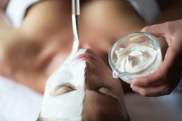Woman's face from above with a white face mask being applied