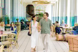 Mick and Angie walking towards the camera through the Orangery at Heythrop Park, a Warner Hotel