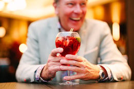 A guest laughing as he holds a cocktail