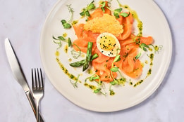 Smoked trout on a white plate with cutlery beside