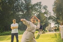 Angie prepares to throw an axe and Mick looks on nervously in the background seeing her pent up rage