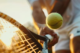 Close up of a tennis racket hitting a tennis ball