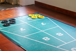 A green and black shuffleboard game board set up for play at Norton Grange, featuring smooth lanes and scoring areas.