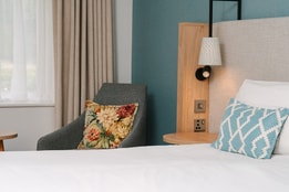 Close-up of a bedroom seating area beside a king-size bed and window.