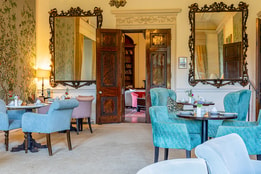 Elegant hotel lounge with ornate mirrors, period features and comfortable seating for afternoon tea.