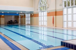 Indoor swimming pool with high ceilings, natural light and relaxing leisure amenities.