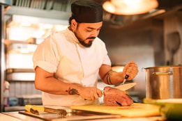 Chef carving freshly roasted meat in an open kitchen