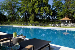 The outdoor pool at The Runnymede on Thames Hotel, featuring a sun lounger and a cocktail that has been brought over from the Lounge bar