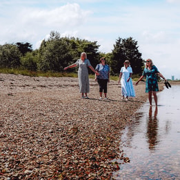 A group of people walking along the sandy beach at Sinah Warren, enjoying the sunny day and ocean views.
