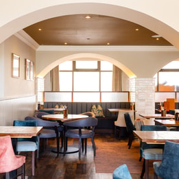 Brightly lit gastropub style restaurant with several tables and chairs
