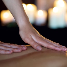 Close up of someone receiving a back massage with warm lit candles in the background