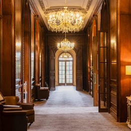 A corridor inside Holme Lacy House, featuring an elegant chandelier and wood panelled walls