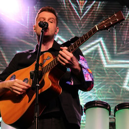 Live in Technicolour performing on stage with a guitar