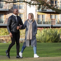 A couple walks hand-in-hand on a grassy path, surrounded by trees and landscaped gardens at Alvaston Hall Hotel