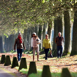 Four people walking along the driveway at Heythrop Park in winter casual wear