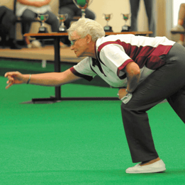 With a smile on her face, a woman leans forward to throw a ball and having a great time playing bowls at a Warner hotel.