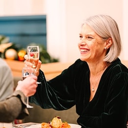 Two guests clinking glasses of prosecco at dinner