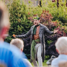 An actor on stage performing at the Outdoor Theatre to an audience of Warner Hotel guests