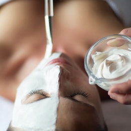 Woman's face from above with a white face mask being applied