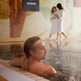 A man enjoying some relaxation time in the spa at a Warner Hotel.