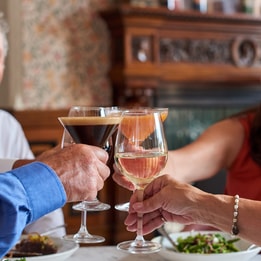 A joyful group toasting with wine glasses at Brasserie32 in Heythrop Park, celebrating together in a vibrant atmosphere.
