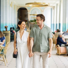 A couple strolls hand-in-hand through the elegant dining area of Heythrop Park Hotel, enjoying a romantic evening together.