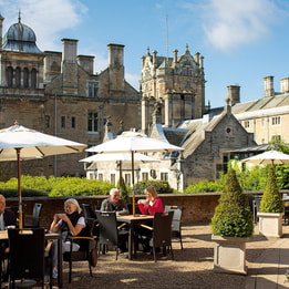 Some guests are enjoying drinks and snacks on the terrace on a warm day at Thoresby Hall Hotel