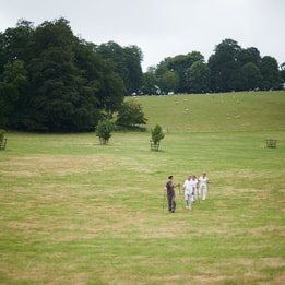 People Nordic walking across a large open park with rolling hills and trees in the background.