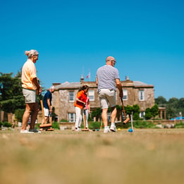 Historic country house hotel with wisteria-clad façade, formal gardens and ornamental fountain.
