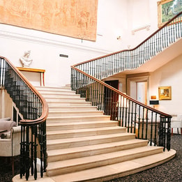 Grand hotel staircase with sweeping balustrades, artwork and elegant lounge seating.