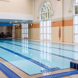 Indoor swimming pool with high ceilings, natural light and relaxing leisure amenities.