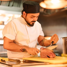Chef carving freshly roasted meat in an open kitchen