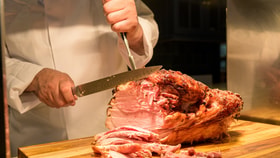 Close up of a chef carving a gammon joint.