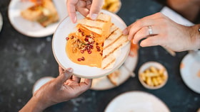 Guests sharing grilled flatbread with dip, garnished with pomegranate seeds, as part of a small plates dining experience.