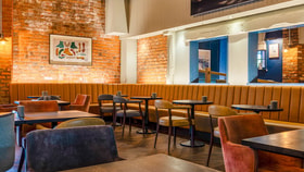 Generating response Copilot said:  Contemporary restaurant seating area with exposed brick walls, upholstered banquette seating and modern dining tables.