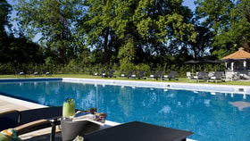 The outdoor pool and lounger at The Runnymede on Thames Hotel, with a cocktail being enjoyed by a guest